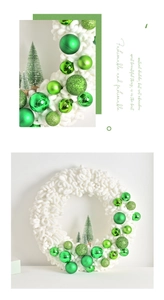 Close-up of plush white Christmas wreath featuring green baubles and miniature tree