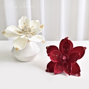 Red and cream decorative Christmas magnolia flowers with glitter in a white ceramic vase