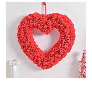 Vue détaillée d'une couronne de roses rouges en forme de cœur sur un mur blanc texturé