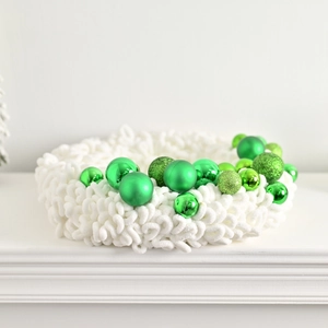 Handcrafted white plush Christmas wreath with decorative green ornaments for festive decor