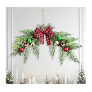 Detail of Christmas pine swag with buffalo plaid bow and ornaments on a white wall