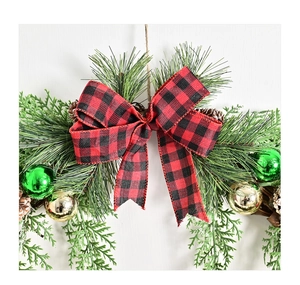 Close-up of Christmas wreath with pine needles, pine cones and red-black buffalo plaid bow