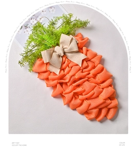 Détail de la couronne carotte en maille orange avec feuilles vertes et nœud en toile