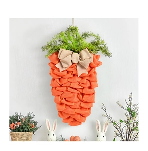 Couronne de Pâques en forme de carotte en toile de jute orange et feuillage vert sur mur blanc