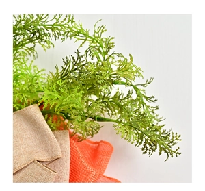 Détail de la couronne de carottes de Pâques avec feuillage vert et nœud en toile de jute