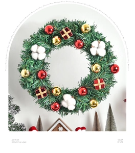 Detail eines Weihnachtskranzes mit grünen Kiefernnadeln, roten Goldkugeln und Watte