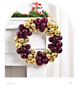 Detail of Christmas wreath featuring metallic gold and burgundy glossy ornaments on white wall
