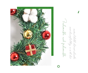 Detailansicht eines Weihnachtskranzes mit grünen Tannennadeln, roter Geschenkbox und Goldkugeln