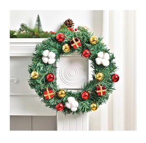 Detail eines Weihnachtskranzes mit roten Kugeln und Baumwolle am weißen Kamin