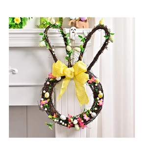 Detail of Easter bunny wreath with yellow plaid bow, faux flowers and speckled eggs on white wall