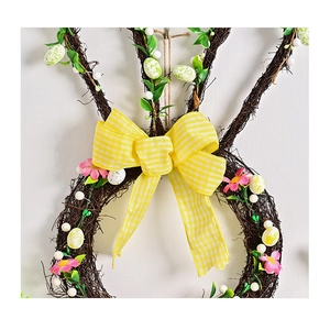 Detail of Easter bunny rattan wreath with gingham bow, pastel eggs and spring flowers