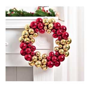 Detail of a festive Christmas wreath with glossy red and gold baubles on a fireplace