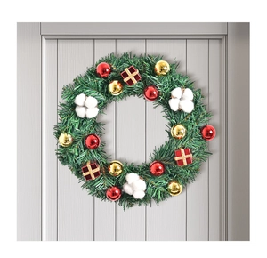 Detail eines Weihnachtskranzes mit Tannennadeln und roten Ornamenten an einer Holztür