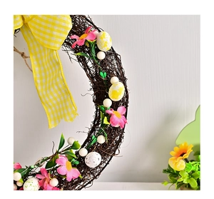 Macro detail of Easter wreath showing natural rattan, pink silk flowers and speckled eggs