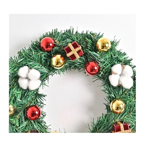 Detail eines Weihnachtskranzes mit Kiefernadeln, roten Ornamenten und Baumwollkugeln