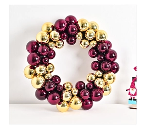 Close-up of a Christmas wreath with glossy gold and burgundy ornaments in multiple sizes
