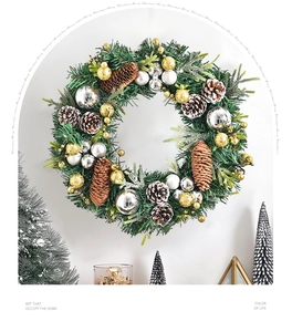 Detail of a Nordic Christmas wreath with pine cones and gold ornaments on a white wall