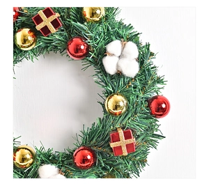 Detail eines Weihnachtskranzes mit roten und goldenen Kugeln, Tannennadeln und Baumwolle