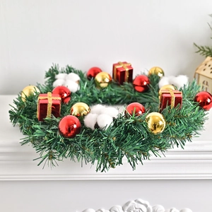 Nordischer Weihnachtskranz mit Tannennadeln, rot-goldenen Kugeln auf weißem Kamin