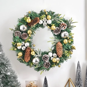 Nordic Christmas pine cone wreath with gold silver ornaments hanging on a white wall