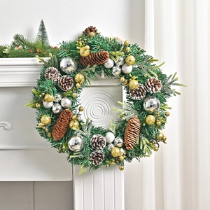 Nordic Christmas wreath with pine cones and baubles hanging on a white fireplace