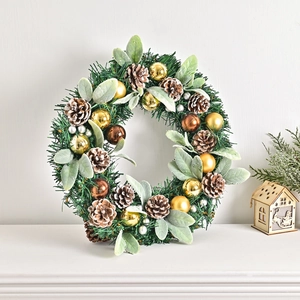 Nordic Christmas pine cone wreath with gold baubles on a white fireplace mantel