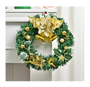 Close-up of a Christmas wreath with gold bells, reindeer, and bow on a white fireplace