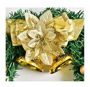 Close-up of a golden Christmas wreath with poinsettia flower, ribbon, and bells