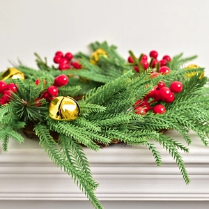 Norfolk pine Christmas wreath with red berries and golden bells on a white mantel