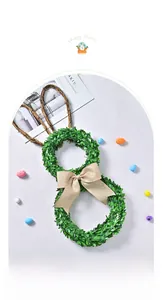 Detail of bunny leaf wreath with burlap bow and colorful Easter eggs on white surface