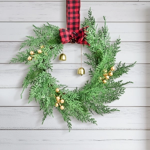 Nordic Christmas wreath with golden berries, buffalo plaid bow, and bells on wood background