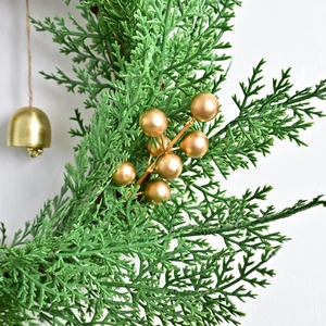 Nordic Christmas greenery branch with golden berries and vintage bells on white wall