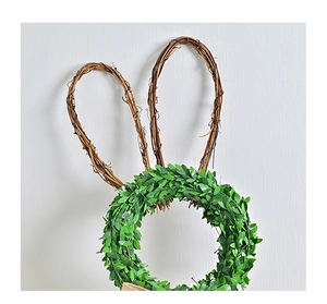 Detail of Easter bunny wreath with green leaves and vine ears hanging on grey wall