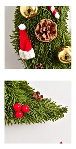 Detail showing pine cones, gold baubles, and red knit hat on Christmas moon-shaped wreath