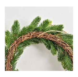 Dettaglio degli aghi di pino verde denso e della base in rattan naturale della ghirlanda di Natale