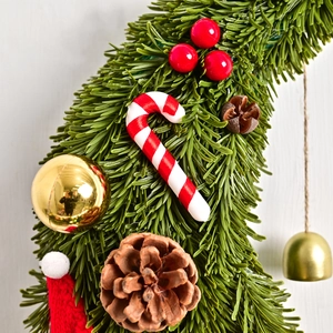 Christmas moon wreath with pine needles, candy canes, berries and ornaments on wood