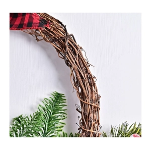 Detail of handcrafted vine base with green pine needles and buffalo plaid fabric decor