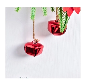 Gros plan sur une cloche de Noël rouge brillante avec corde de jute et aiguilles de pin