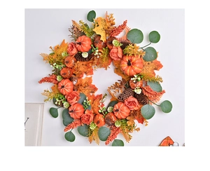 Detail of autumn wreath with orange pumpkins, pine cones, and maple leaves on white wall