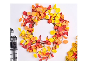 Close-up of fall wreath with maple leaves and small pumpkins on a white wall