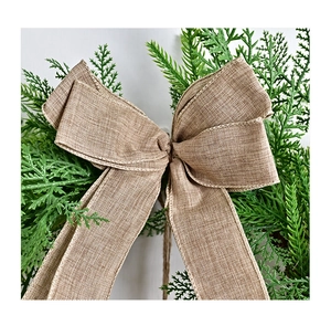 Makroaufnahme einer rustikalen Juteschleife und grüner Tannennadeln am Weihnachtskranz