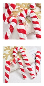 Detail of plush candy cane ornament with red and white stripes and gold snowflake prints