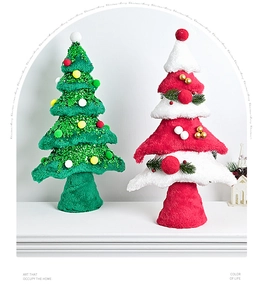 Detailed view of mini plush Christmas trees with sequins and festive ornaments on white stage