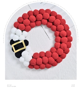 Detail of plush Christmas Santa wreath with red white and black pom poms and gold belt buckle