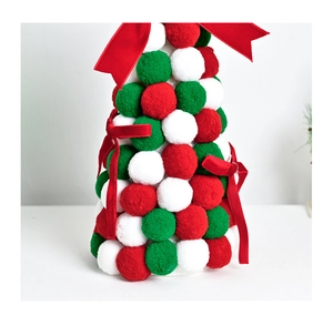 Close-up of fluffy pom-poms and red velvet bows on a desktop Christmas tree ornament