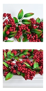 Detailed close-up of red berries and green leaves on Christmas artificial wreath decoration