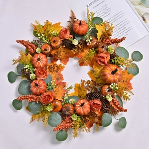 Fall wreath with orange pumpkins, maple leaves, pine cones and flowers for front door decor