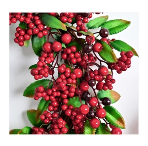 Close-up of lifelike red winter berries and dark green holly leaves for holiday decor