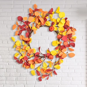 Autumn harvest wreath with colorful eucalyptus leaves and orange pumpkins on white wall