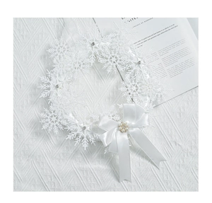 Dettaglio ghirlanda di fiocchi di neve con strass ed elegante fiocco di raso con perle